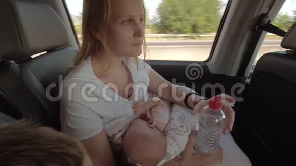 妈妈在移动的汽车里照顾婴儿和喝水视频的预览图
