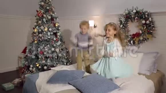 两个快乐的孩子在床上跳跃圣诞节视频的预览图