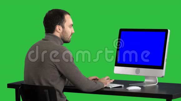 商人在绿色屏幕上使用电脑Chroma键蓝色屏幕模拟显示视频的预览图
