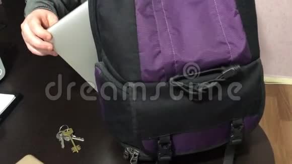 一个年轻人把笔记本电脑放在背包里他从桌子上拿起钥匙拿起电话离开了视频的预览图