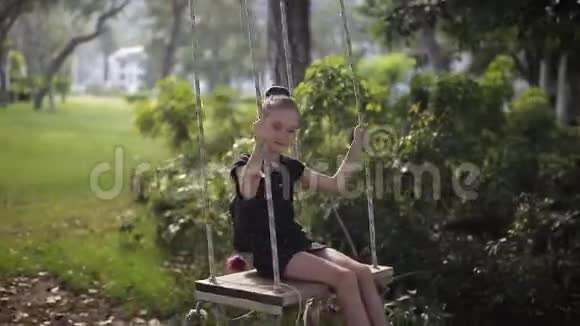 小女孩在大自然森林公园的秋千上摇摆视频的预览图