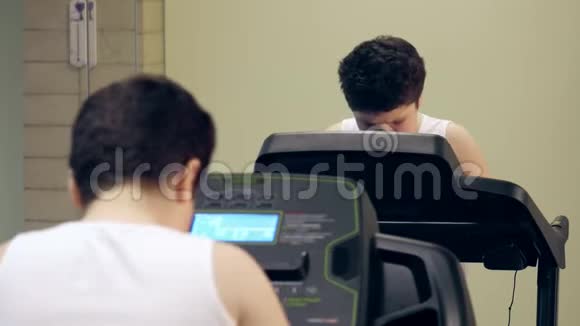 在室内健身房跑步机上训练一个肥胖的小男孩视频的预览图