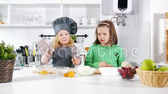 两个学龄前的小女孩在做奶酪蛋糕和甜点时玩得很开心视频的预览图