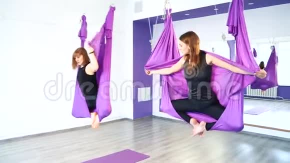 两个年轻女子在工作室的吊床上练习瑜伽视频的预览图