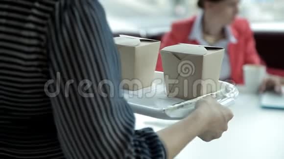两个年轻的商务女孩在午餐时坐在笔记本电脑上吃面条工作午餐视频的预览图