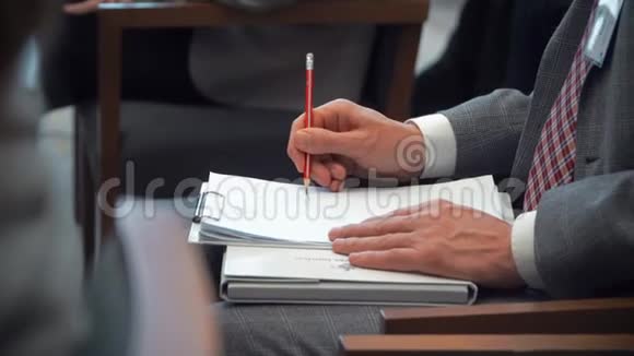 会议期间人们用铅笔在笔记本上记笔记视频的预览图