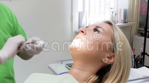 牙科医生用特殊的镜子为病人做牙齿检查特写4k镜头视频的预览图
