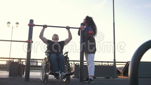 坐轮椅的残疾人站在户外年轻女子旁边的酒吧里视频的预览图