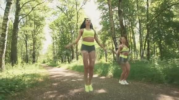 两只年轻的雌性在公园里缓慢地跳绳健康生活方式视频的预览图