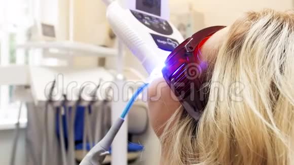 紫外线灯在牙齿美白过程中躺在牙椅上的年轻女性特写4k视频视频的预览图