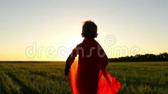 一个穿着超级英雄服装穿着红色雨衣的孩子正在绿色草坪上奔跑背景是一场日落模拟视频的预览图