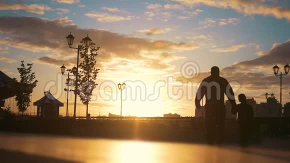 男人带着一个孩子在码头散步过去的男人在日落时带着一个坐轮椅的年轻女人视频的预览图