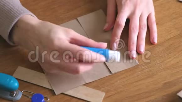 女人用牛皮纸做纸袋双手特写把纸粘上视频的预览图