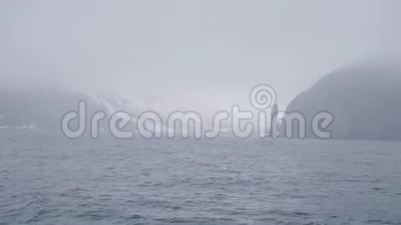 雾霭中的雪山和悬崖从帆船上可以看到寒冷的海景视频的预览图