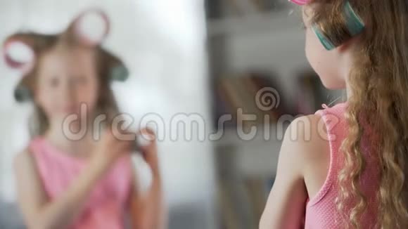 可爱的女孩像妈妈一样在镜子前起自己的头发视频的预览图