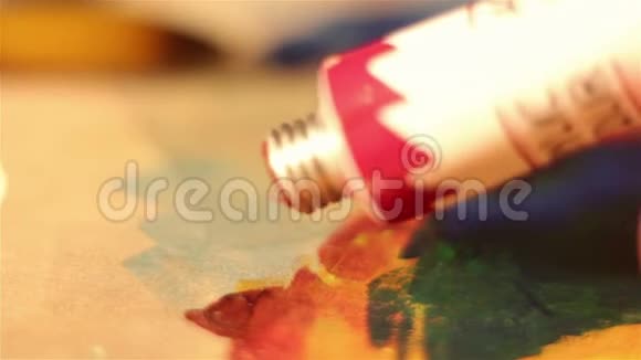 艺术家把管里的红色颜料挤到调色板上视频的预览图