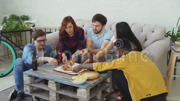 一群年轻的朋友在家里开派对吃披萨从桌子上拿下来学生聊天玩得开心视频的预览图