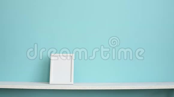 现代客房装饰与相框模型白色的架子贴在青绿色的墙上用手放下盆栽的龙葵视频的预览图