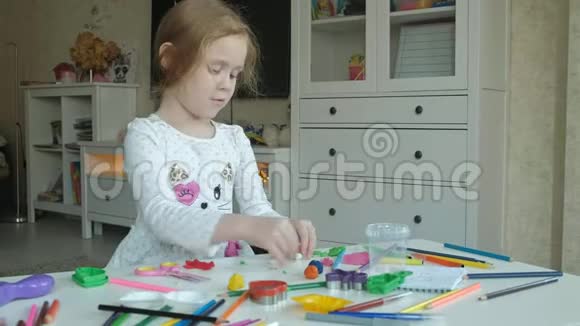 快乐的小女孩玩橡皮泥用手滚球数字和彩色铅笔躺在桌面上视频的预览图