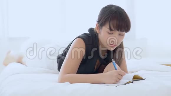 美丽的肖像年轻的亚洲妇女放松躺在床上思考想法和写书或日记视频的预览图