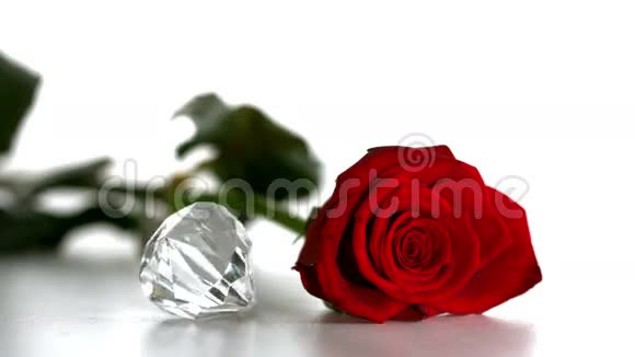 钻石在白色背景的红玫瑰旁边旋转视频的预览图