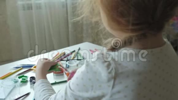 一个小女孩玩塑料线用剪刀剪成碎片图形和彩色铅笔躺在桌面上视频的预览图