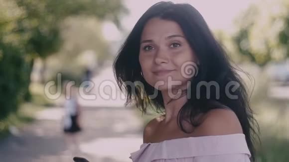 美丽的年轻女子在城市的街道上转过身来对着镜头微笑慢动作视频的预览图