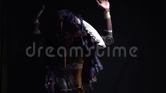 穿着仪式服装和装饰品在黑色背景上跳舞的非洲男人动作缓慢视频的预览图