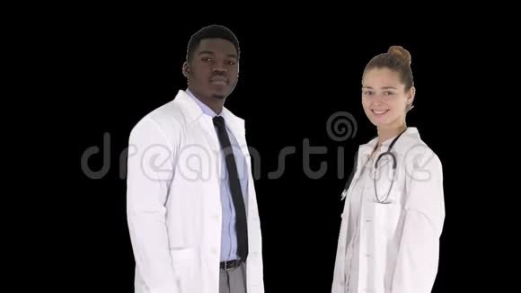 两个白种人和非裔美国人微笑的医生站在镜头前阿尔法频道视频的预览图