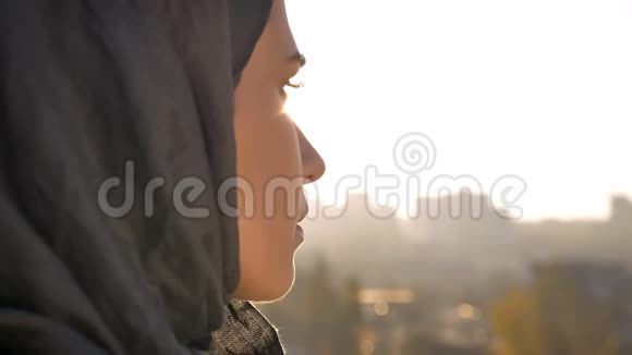 戴头巾的年轻迷人女性的特写后景展望城市的转折和镜头视频的预览图