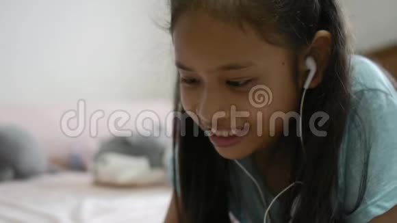 可爱的女孩从手机听音乐耳机躺在床上视频的预览图