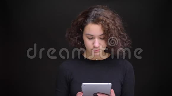 在镜头前用平板电脑拍摄一幅年轻迷人的留着卷发的白种人女性的特写肖像视频的预览图