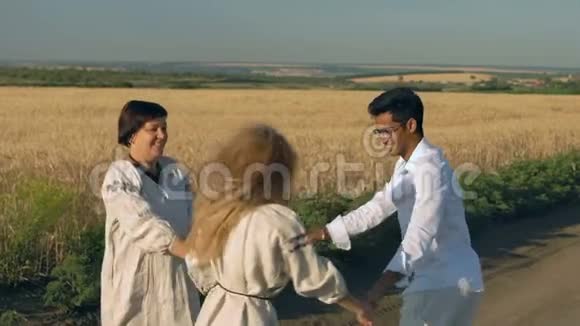 慢动作戴眼镜的印度男人和两个穿国家服装的女人在麦田里跳舞视频的预览图