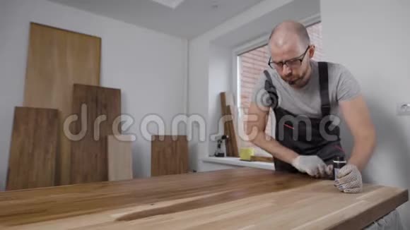 整体工人和手套工人在室内为木制面板涂油视频的预览图