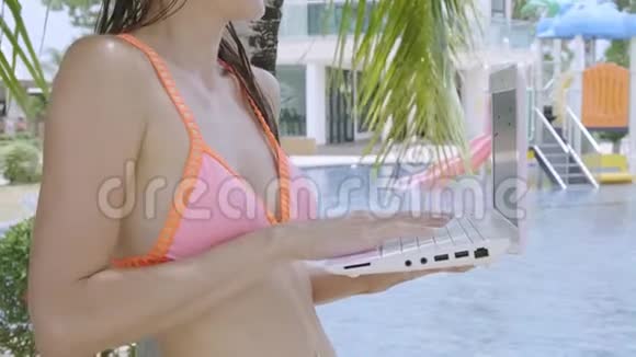 年轻的女性自由职业者坐在游泳池附近的笔记本电脑假期里很忙远程工作的概念特写视频的预览图