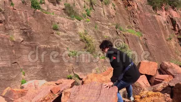 老妇人爬过山上堆积如山的石头视频的预览图