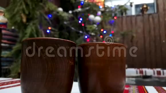 两杯覆盖葡萄酒背景的圣诞花环和五颜六色的灯光节日快乐或新的概念视频的预览图