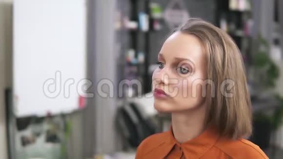 一个金发女郎坐在椅子上一个化妆师正用脸喷雾器在她的脸上她的化妆已经视频的预览图