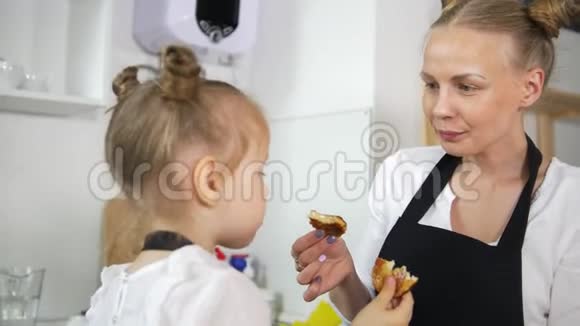 可爱的小女孩和她的妈妈一起吃自制的煎饼视频的预览图