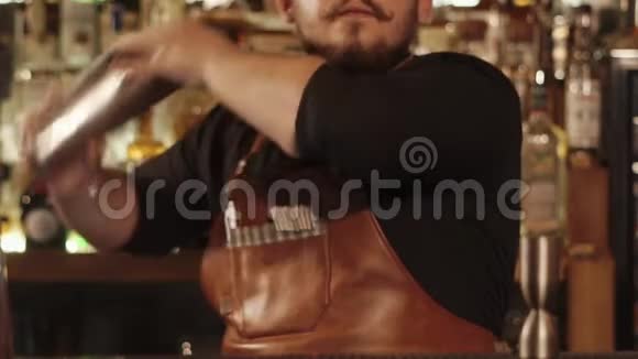 他用鸡尾酒的原料摇着摇床近距离拍摄酒吧间的手视频的预览图