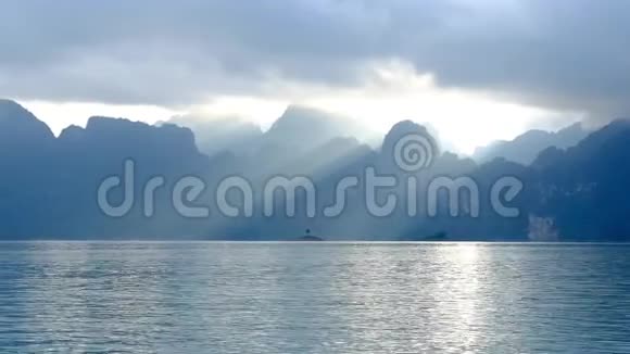 太阳透过云层穿过山和湖视频的预览图