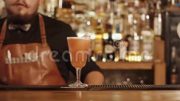蓄胡子的酒吧老板用手把装有混合饮料的玻璃杯移到相机上视频的预览图