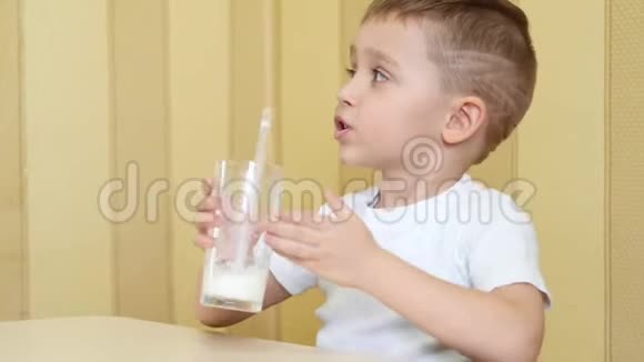 孩子通过吸管从杯子里喝牛奶表现出快乐和一只手的拇指视频的预览图