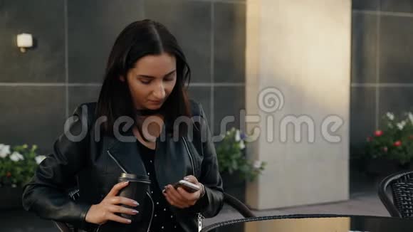 一个年轻的女人坐在咖啡馆里使用智能手机视频的预览图
