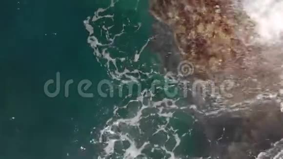 空中射击垂直方向向下海浪溅起蓝色和绿松石的颜色和火山的海岸线视频的预览图