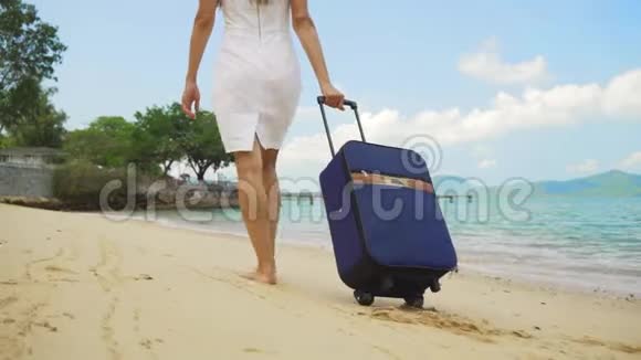 商务女性带着一个手提箱沿着美丽的大海的海岸散步自由职业概念期待已久的休闲概念视频的预览图