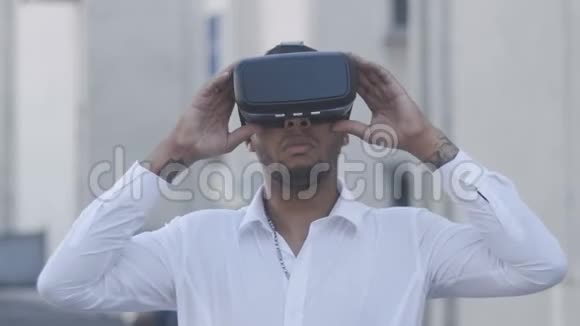非裔美国人年轻的商人穿着白色衬衫戴着虚拟现实头盔户外活动视频的预览图