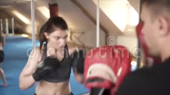 漂亮的女人在健身房训练拳击从训练员回来看视频的预览图