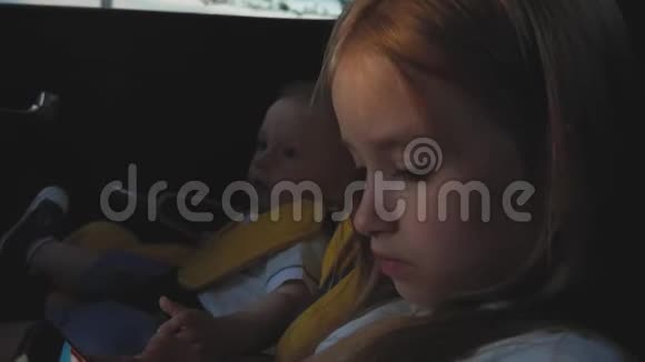 可爱的小女孩坐在汽车座位上玩智能手机视频的预览图