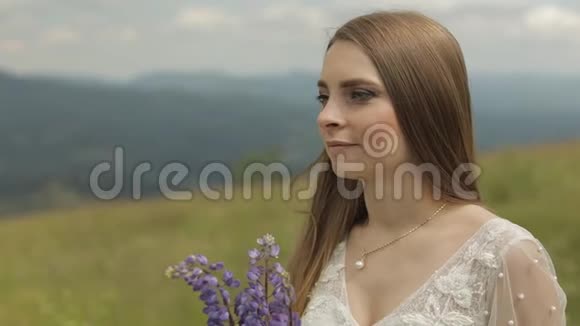 美丽的新娘穿着婚纱留在山上带着鲜花视频的预览图